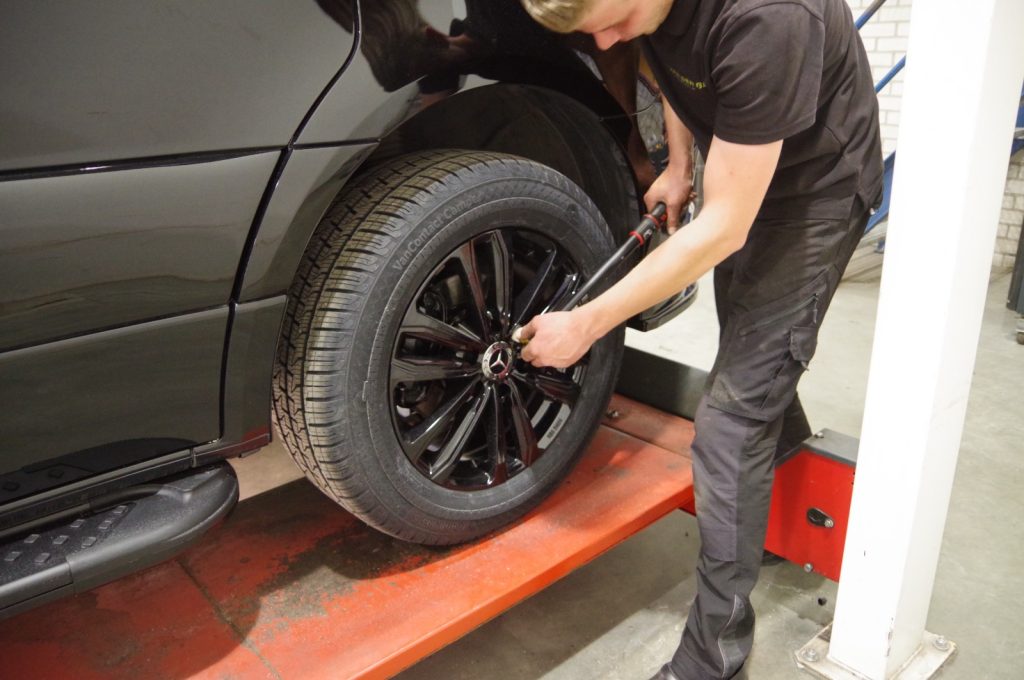 Detail van handen en gereedschap bij het wiel en de remmen in de werkplaats